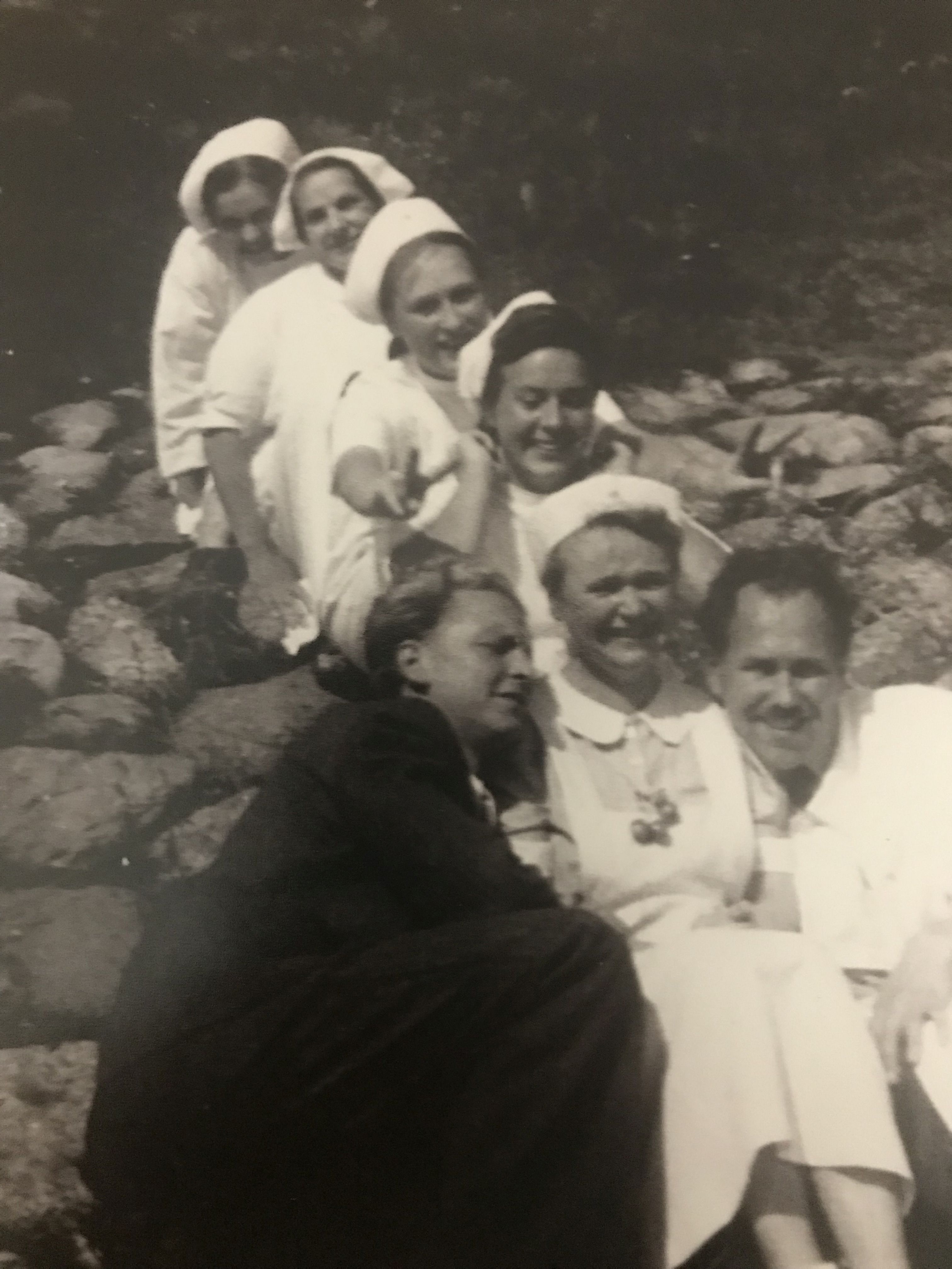 Czarno- białe zdjęcie przedstawia pięć kobiet w białych strojach, tworzą one pociąg i dw&oacute;ch mężczyzn po lewej i prawej stronie. 